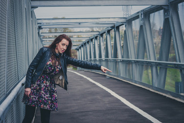 Pretty girl with long hair hitchhiking on a bridge