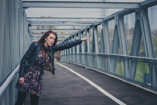 Pretty girl with long hair hitchhiking on a bridge