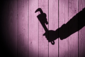 Human hand shadow with adjustable wrench  on the wood background