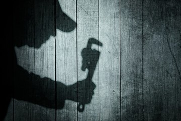 Shadow of a man with wrench  on natural wooden background