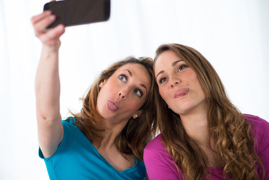 portrait of two beautiful girls making a funny selfie