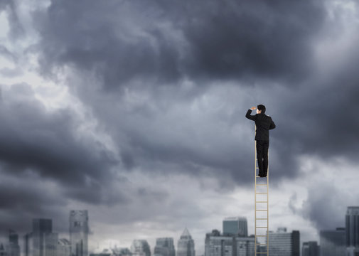 Businessman climbing on a ladder over a city looking ahead