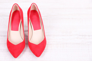 Beautiful red female shoes, on wooden background