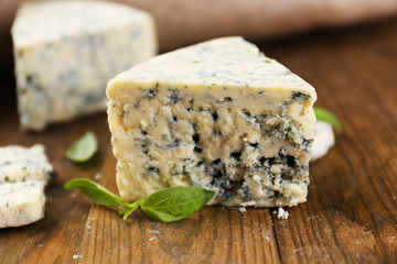 Tasty blue cheese with basil, on wooden table