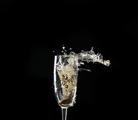 Glass of champagne with splash, on black background