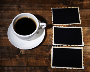Coffee cup and old blank photos, on wooden background