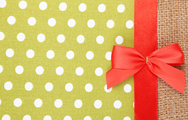 Sackcloth with color ribbon and bow on color fabric background