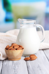 Almond milk in jug with almonds in bowl,