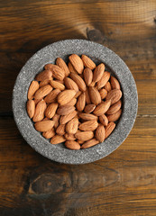 Almonds in bowl on color wooden background