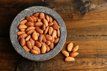 Almonds in bowl on color wooden background