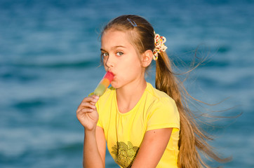 girl eating colorful tasty ice cream on a background of blue sea