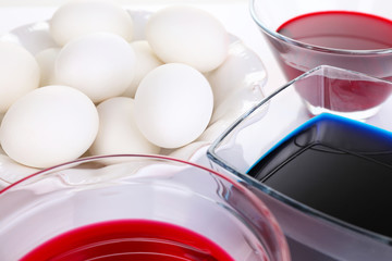 Eggs with liquid colour in glass bowls close up