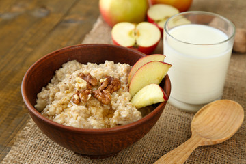 Tasty oatmeal with nuts and apples on wooden table
