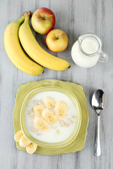 Tasty oatmeal with bananas and milk on wooden table