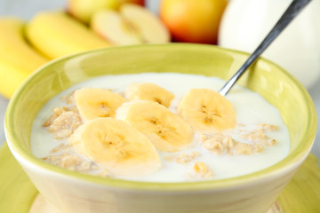 Tasty oatmeal with bananas and milk on table close up