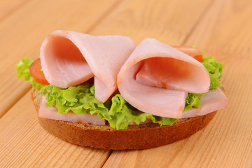 Delicious sandwich with lettuce and ham on table close-up