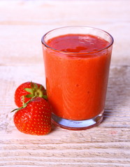 Strawberry smoothie in glass with two berries