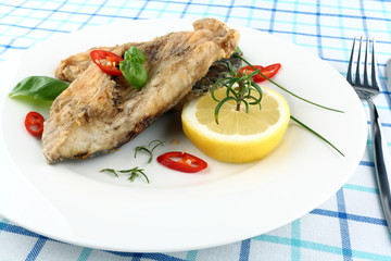  Fried fish on white plate with fork and knife