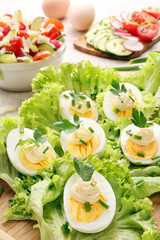Eggs with mayonnaise and vegetables on wood background
