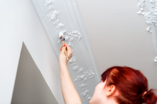 junge frau streicht stuckdecke