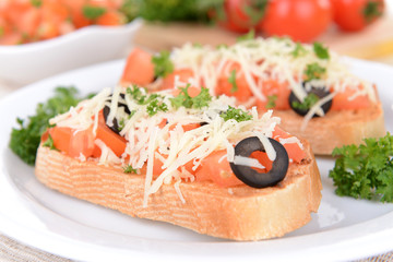 Delicious bruschetta with tomatoes on plate on table close-up