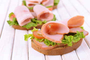 Delicious sandwiches with lettuce and ham on table close-up