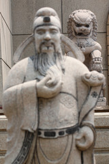 Statues of Chinese deity in focus lion sculpture.