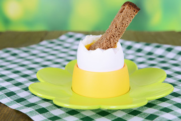 Boiled egg in egg cup on table on bright background