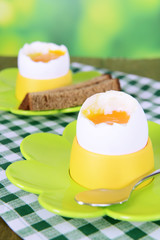 Boiled eggs in egg cups on table on bright background