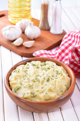 Delicious mashed potatoes with greens in bowl on table close-up