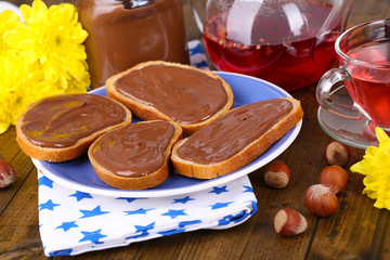 Bread with sweet chocolate hazelnut spread on plate on table