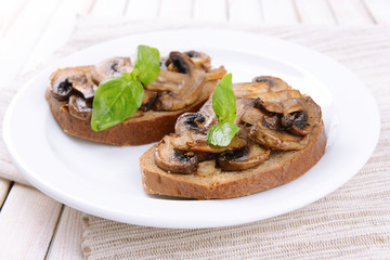 Delicious bruschetta with mushrooms on plate on table close-up