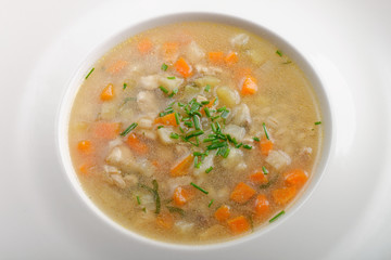 Bone Broth in Small Soup Bowl Served with Fresh Herbs, Garlic