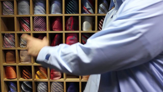 A man trying to choose the right tie for his shirt - picks one but it doesn&acute;t fit than chooses another one which is an ideal combination - shows thumb up
