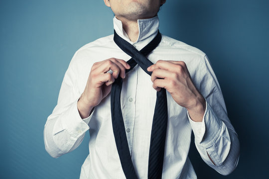 Young man tying his tie