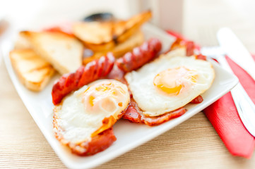 close-up of healthy breakfast with fried eggs, bacon, sausages