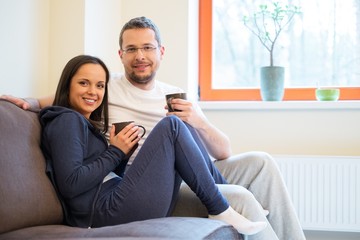 Young cheerful couple on a sofa in home interior