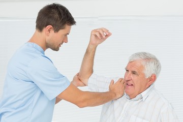 Obraz premium Physiotherapist assisting senior man to stretch his hand
