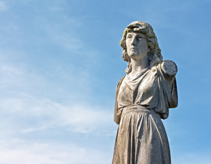 A Female weathered statue in ancient graveyard