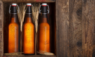 Beer bottles with wheat stems in old wooden crate