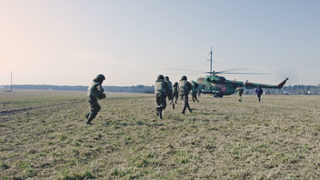 Soldiers with guns are running to  helicopter.