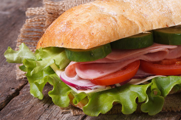 ciabatta sandwich with ham and vegetables macro on table.