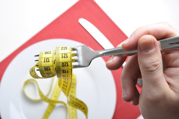 fork wrapped in measure tape in diet and overweight concept