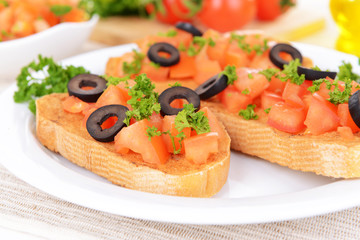 Delicious bruschetta with tomatoes on plate on table close-up