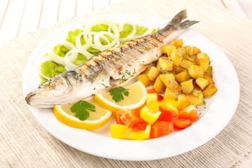 Delicious grilled fish on plate on table close-up