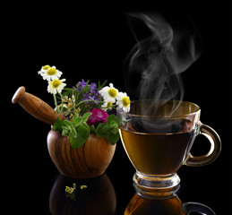 Cup of hot tea and mortar with fresh herbs