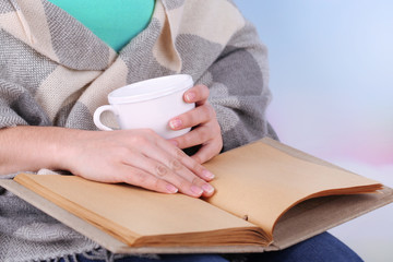 Woman reading book and  drink coffee or tea, close-up