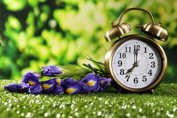 Digital alarm clock on green grass, on nature background