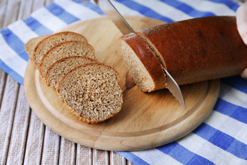 Female hands cutting bread on wooden board, close-up