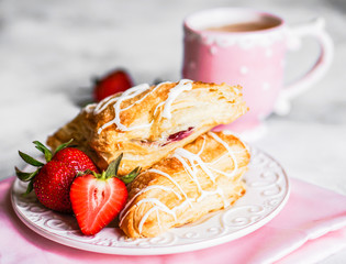 Fresh croissants with strawberries on wooden background